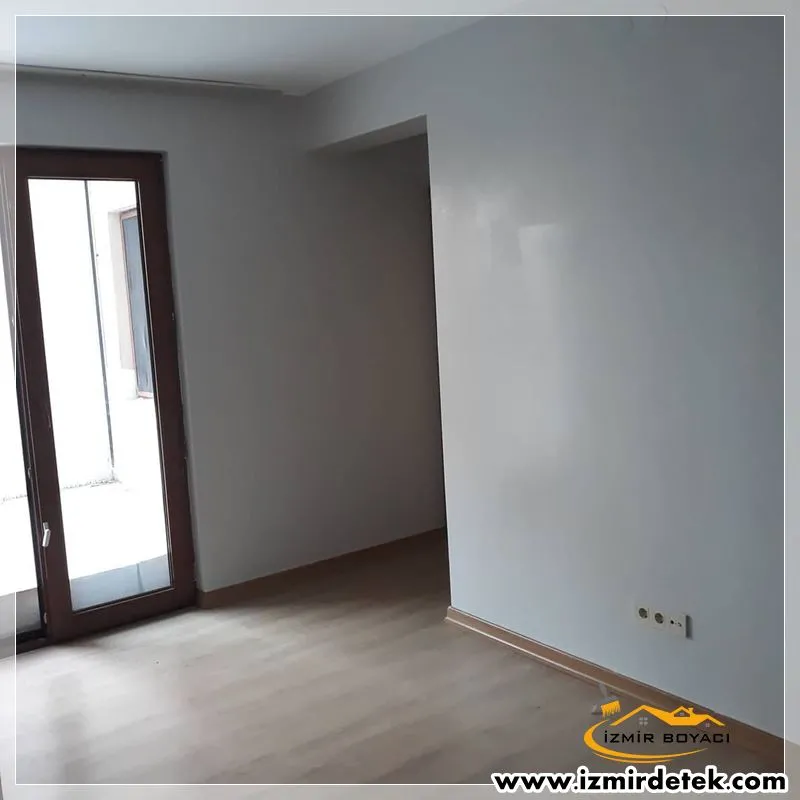 Gri tonlu duvarları yeni boyanmış, balkon kapılı boş bir oda
